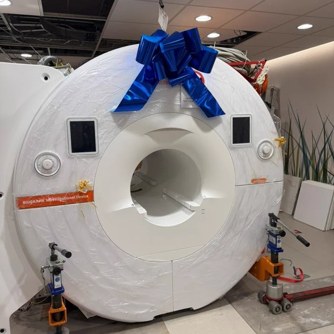 PET-MR scanner pictured wrapped in plastic with a big blue bow on top.