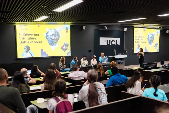 Five researchers are sitting on stage, in front of a screen that writes "Engineering the Future: Battle of Ideas". In the foreground, we can see a room full of attendees who are listening to the event.
