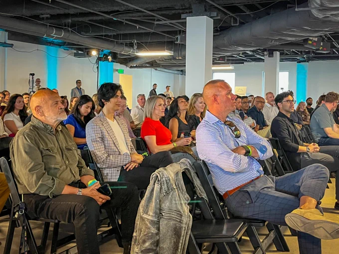 Diverse group of adults attentively listening during a modern indoor seminar at Colorado StartUp Week. 